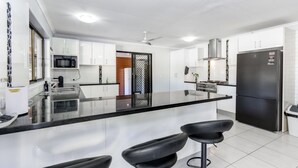 A modern kitchen with white cabinets, a black countertop, a stainless steel refrigerator, and a gas stove.
