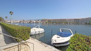A marina with boats docked, a walkway, and buildings in the background. - Apartment in Empuriabrava with Canal Views (Empuriabrava)