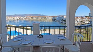 A dining table set for four with a view of a marina and cityscape. - Apartment in Empuriabrava with Canal Views (Empuriabrava)