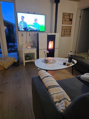 A living room with a television, a fireplace, a round coffee table, and a sofa. - Lovely newer holiday home near beautiful beach (Juelsminde)