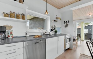 A modern kitchen with white cabinetry, a stainless steel dishwasher, and a window above the sink. - Lovely newer holiday home near beautiful beach (Juelsminde)