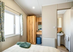 Quarto com cama, guarda-roupa, radiador e banheiro visível por uma porta aberta.