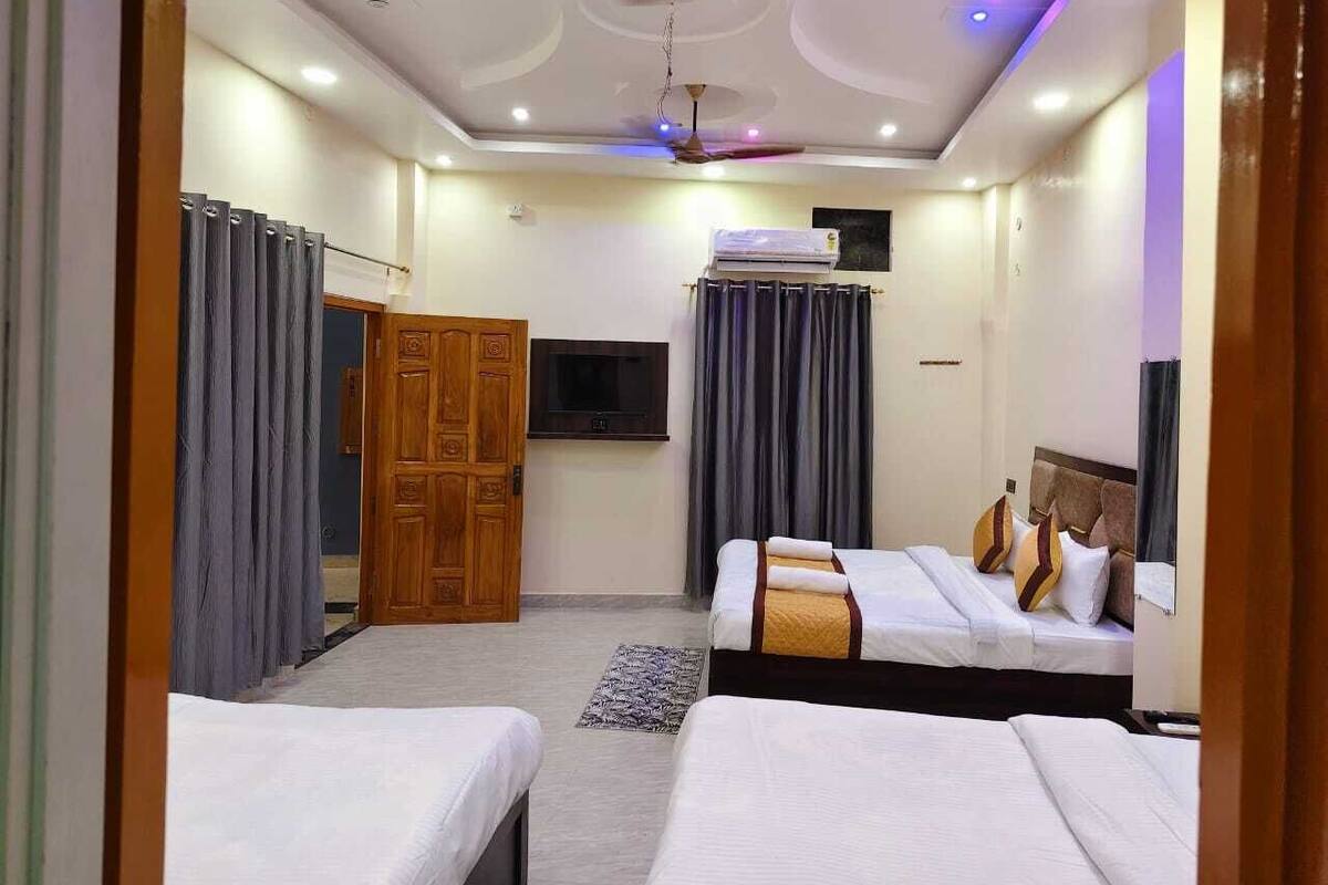 A hotel room with two beds, a ceiling fan, a flat-screen TV, and a wooden door.