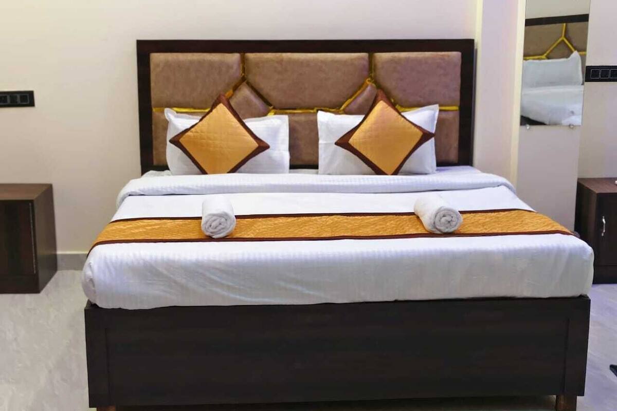 A neatly made bed with a dark headboard, white linens, and decorative pillows.