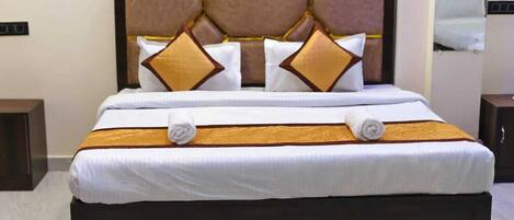 A neatly made bed with a dark headboard, white linens, and decorative pillows.