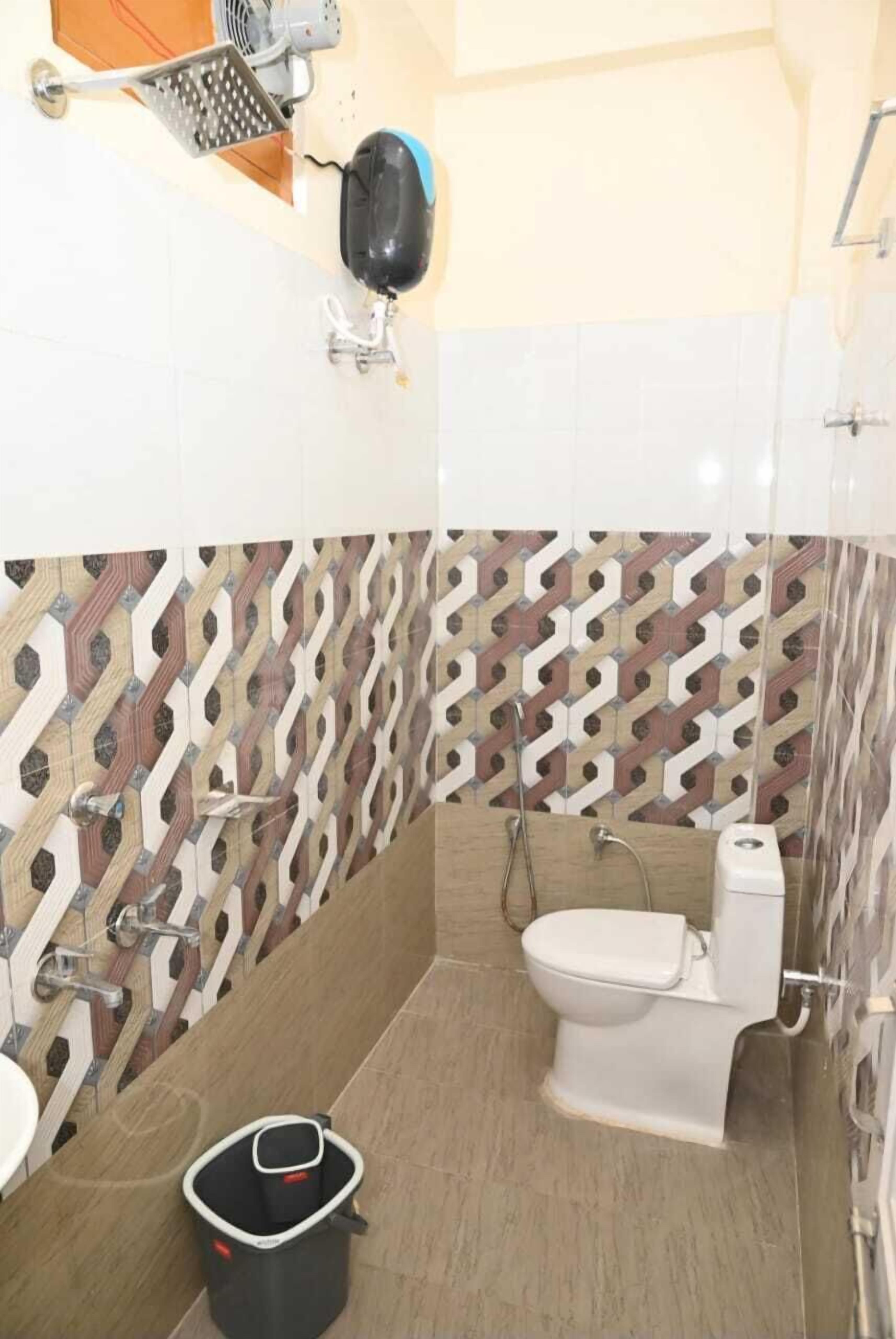 Un baño con salpicadero de azulejos estampados, inodoro, lavabo y zona de ducha.