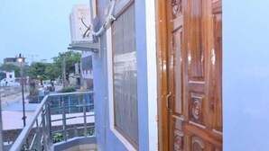 A balcony with a wooden door, a satellite dish, and a view of the street. - De Classico Residency (Ayodhya)