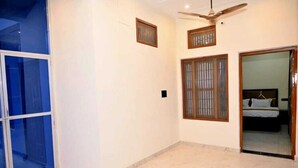 A room with a ceiling fan, a bed with a headboard, and a sliding glass door. - De Classico Residency (Ayodhya)