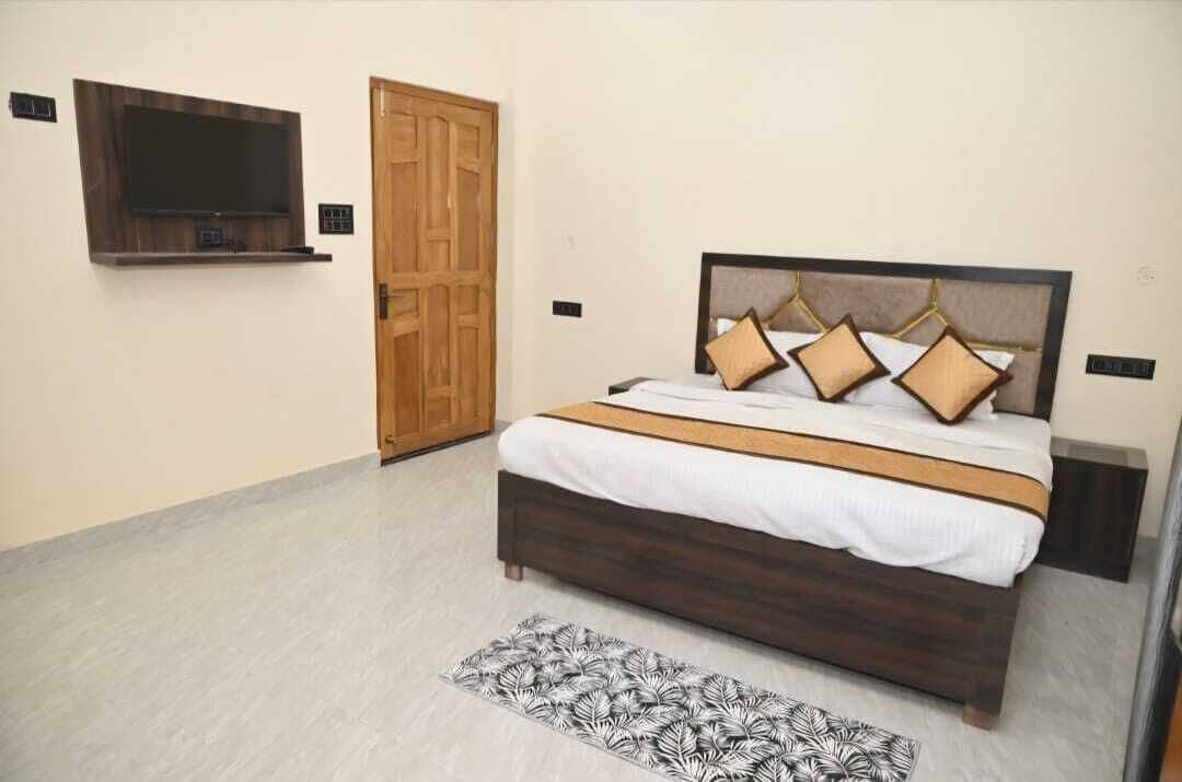 Un dormitorio con cama, televisor montado en la pared y puerta de madera.