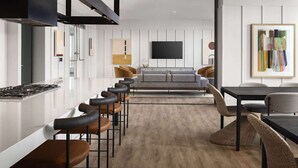 A modern kitchen with a gas stove, bar stools, a grey sofa, and a dining table with chairs. - Penthouse High-rise Ocean City Views (San Diego)