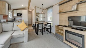 A modern kitchen with a dining area, a sofa, and a TV.