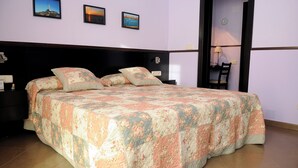 A neatly made bed with floral bedding, a wooden headboard, and a nightstand with a lamp. - LA ESTANCIA DEL RINCON (Cartagena)