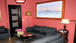 A living room with a dark gray sofa, a coffee table with a vase of flowers, a lamp, and a framed picture of a lighthouse on the wall. - LA ESTANCIA DEL RINCON (Cartagena)
