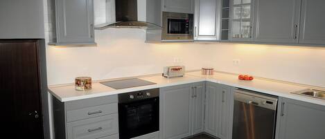 A modern kitchen with grey cabinets, a built-in oven, microwave, and dishwasher.