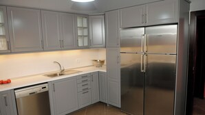 A modern kitchen with grey cabinets, a stainless steel dishwasher, and a large Bosch refrigerator. - LA ESTANCIA DEL RINCON (Cartagena)