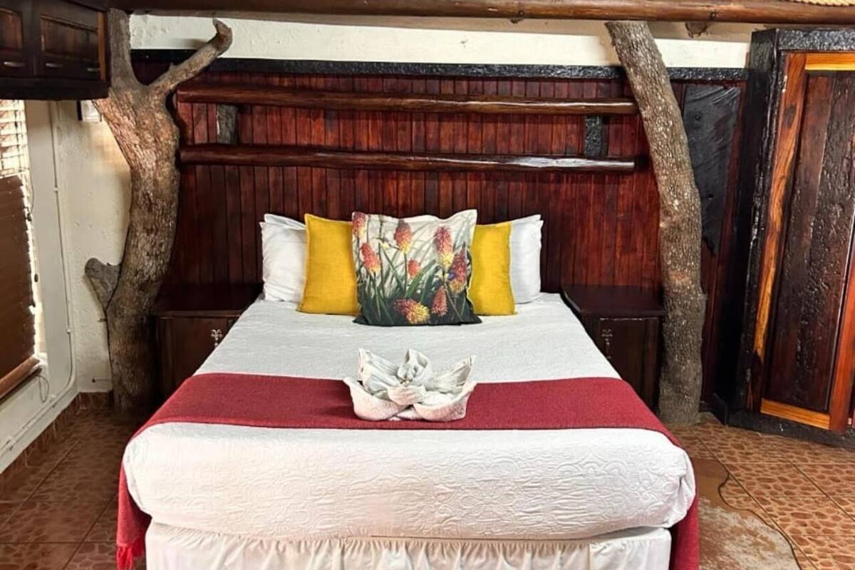 A bed with a red blanket, white pillows, and a floral pillow.