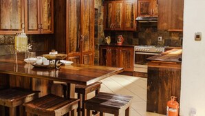 Una cocina con armarios de madera, una estufa y una mesa de comedor con bancos.