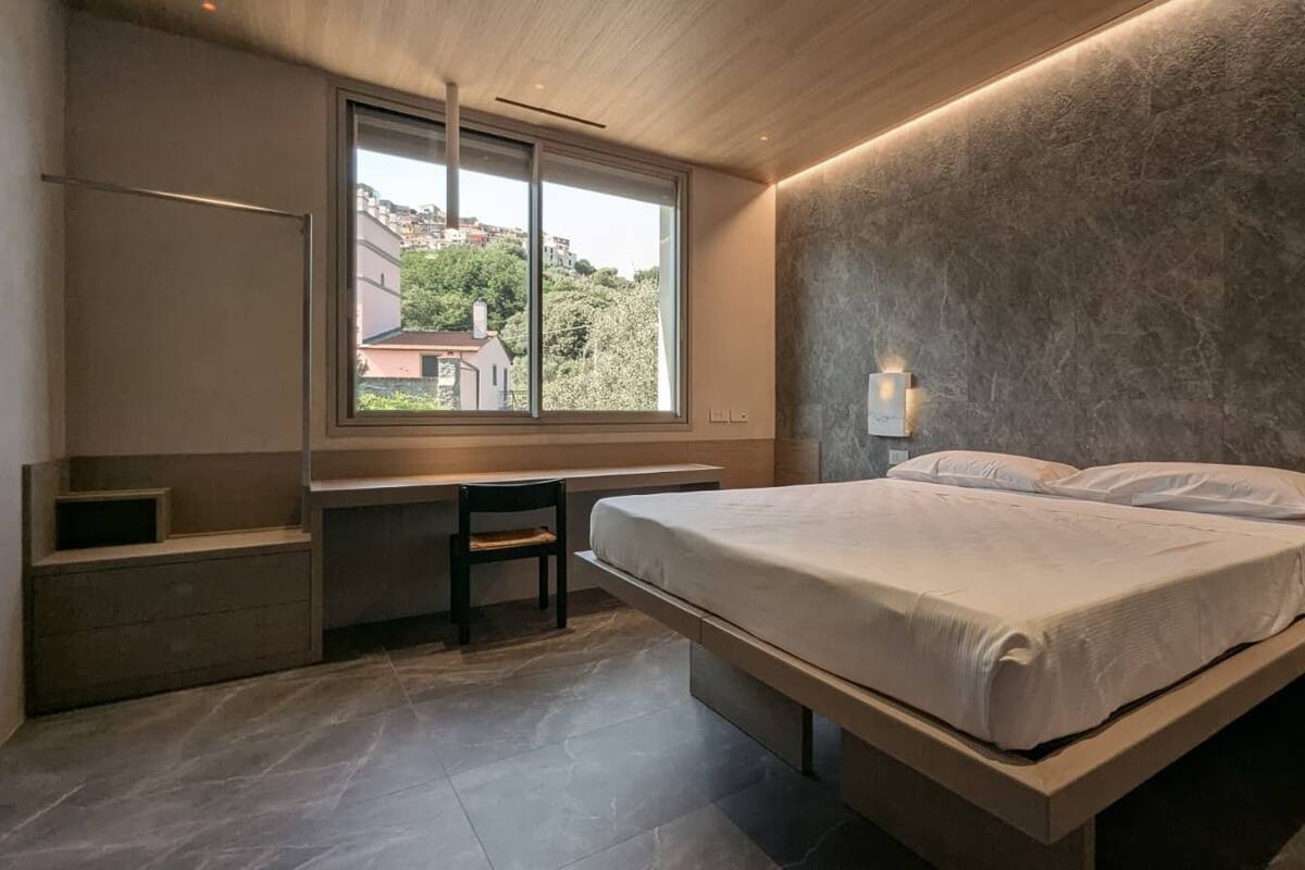 Un dormitorio con una cama, un escritorio y una ventana.