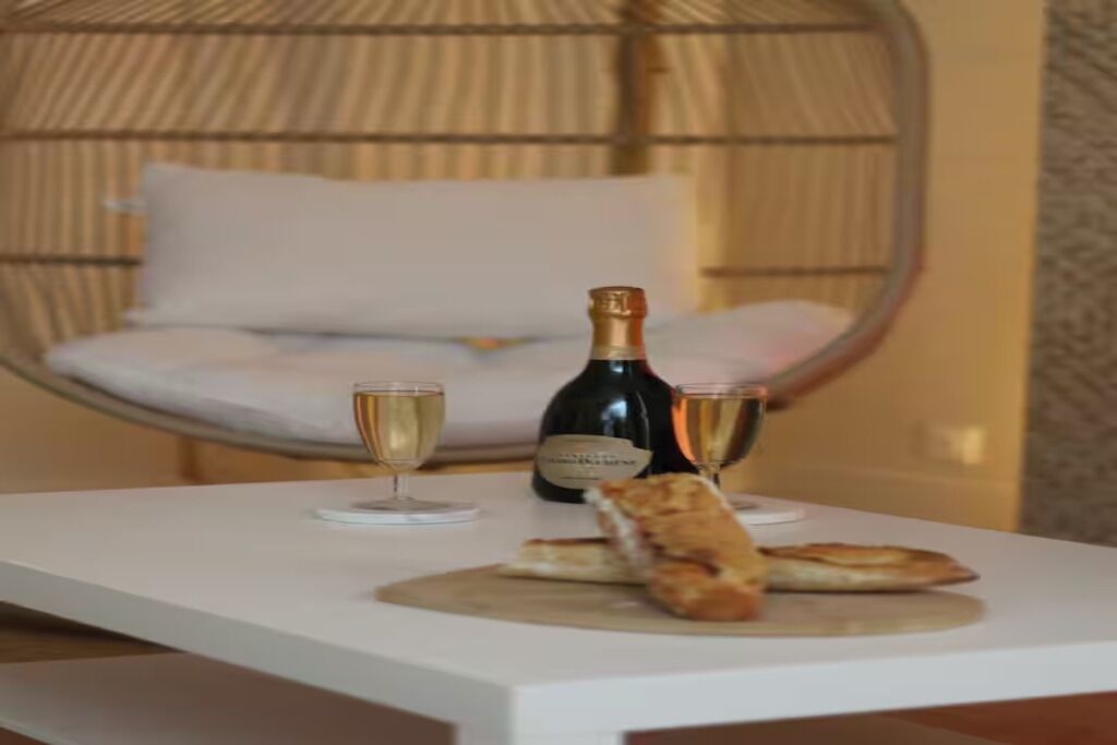 A white table with a bottle of champagne, two glasses, and two pieces of bread.