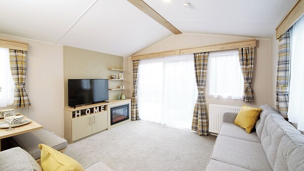A modern living room with a flat-screen TV, sofa, and a fireplace. - 2 bedroom accommodation in Talacre, Holywell (Talacre, Holywell)