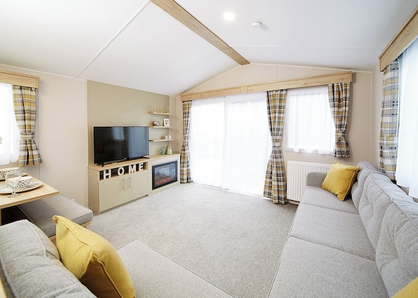A modern living room with a flat-screen TV, sofa, and a fireplace. - 2 bedroom accommodation in Talacre, Holywell (Talacre, Holywell)