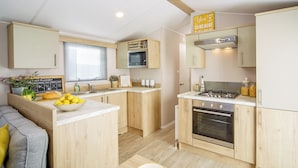 A modern kitchen with wooden cabinets, a built-in oven, and a gas stove. - 2 bedroom accommodation in Talacre, Holywell (Talacre, Holywell)
