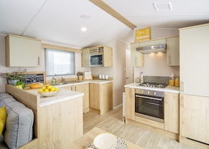 A modern kitchen with wooden cabinets, a built-in oven, and a gas stove. - 2 bedroom accommodation in Talacre, Holywell (Talacre, Holywell)