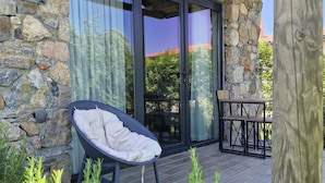 A stone building with a glass door, a wicker chair, and a table with chairs outside. - Mavriya (Ezine)