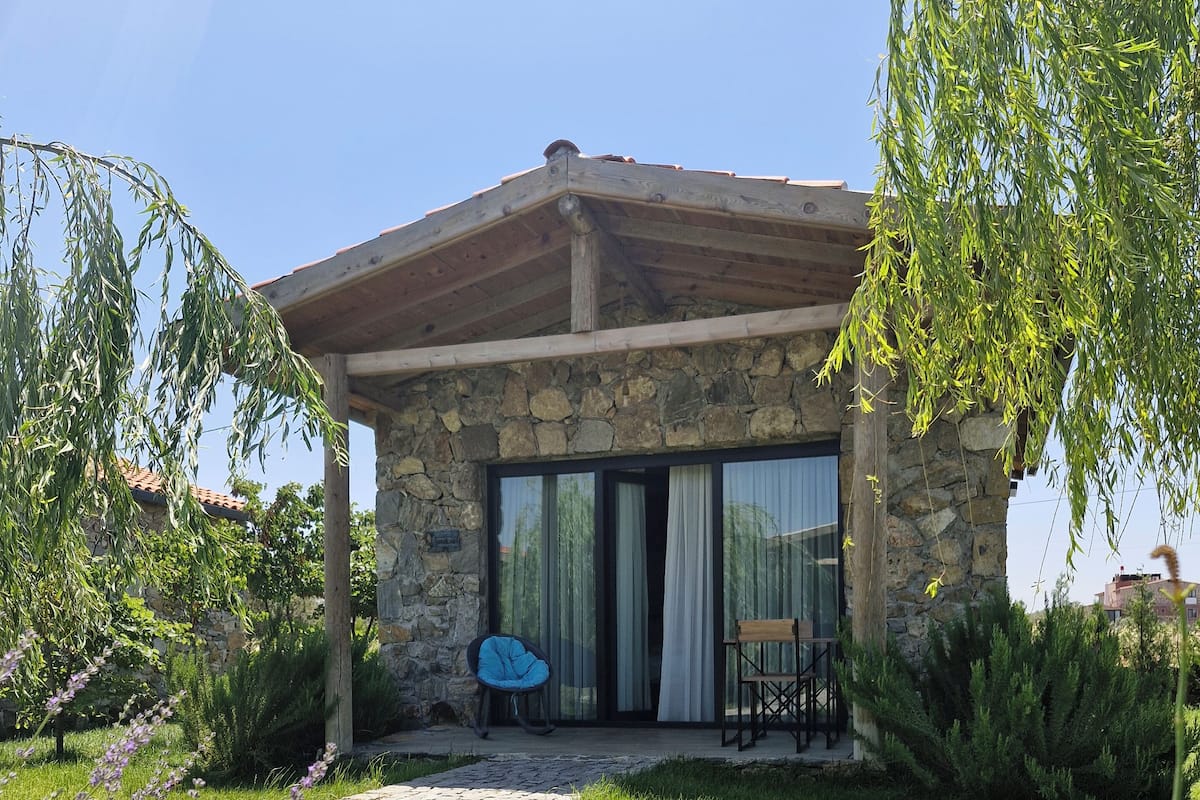 A stone building with a covered patio, a stone pathway, and a grassy area with lavender.