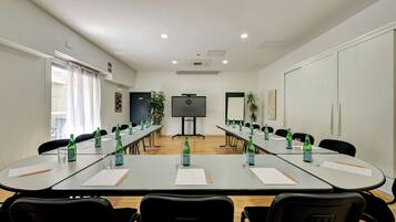Une salle de conférence équipée d’une longue table, de chaises, d’un écran de projection et d’un tableau blanc.