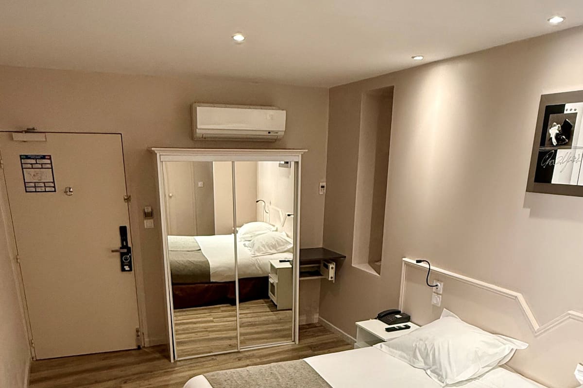Une chambre d’hôtel avec un lit, une table de chevet et un miroir.