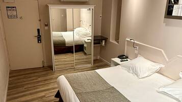 Una habitación de hotel con cama, mesita de noche y espejo.