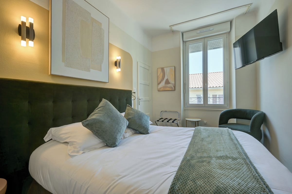 Une chambre d’hôtel dotée d’un grand lit, d’un téléviseur à écran plat fixé au mur et d’une fenêtre donnant sur l’extérieur.