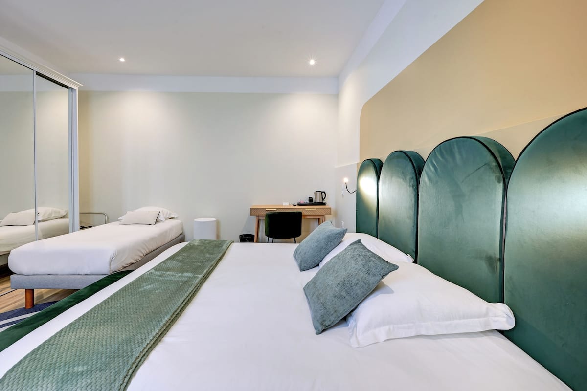 Une chambre d’hôtel comprenant un lit, deux tables de chevet, un bureau, une chaise et un grand miroir.