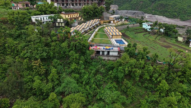 A hotel with multiple buildings, a swimming pool, and lush greenery surrounding the property. - Fillow Casa Hills (Narendra Nagar)