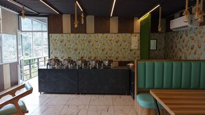 A restaurant interior with a counter, seating, and a view through large windows. - Fillow Casa Hills (Narendra Nagar)