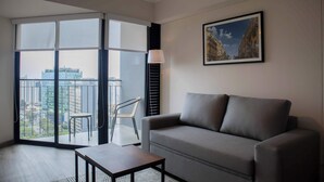 A modern living room with a grey sofa, a wooden coffee table, a chair, and a large window offering a city view. - w* | Awesome 2BR Apartment in Miraflores (Lima)