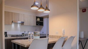 A modern kitchen with granite countertops, stainless steel appliances, and wooden cabinets. There are three bar stools and a small island with a built-in sink. - w* | Awesome 2BR Apartment in Miraflores (Lima)
