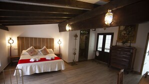 A bedroom with a large bed, wooden beams, a dresser, and two wall-mounted lamps. - RUSTIC & ROMANTIC ROOM (Cuevas de Almanzora)