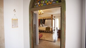 Une chambre à coucher avec un lit à baldaquin, un lustre et une vue sur une autre pièce comprenant un lit et des rideaux.
