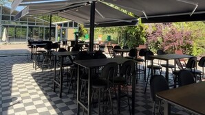 An outdoor cafe with checkered flooring, tables, and chairs under a large canopy. - Villapark (Bartin)