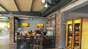 A bar area with a wooden counter, black bar stools, a ceiling fan, and shelves with bottles. - Villapark (Bartin)