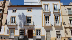 Ein mehrgeschossiges Gebäude mit Balkonen und einem zentralen Eingang, mit dem Schild "El Palacete".