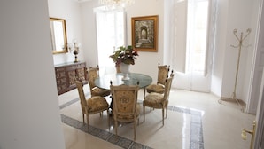 A dining area with a round table, six chairs, a chandelier, a large mirror, and a framed picture on the wall.
