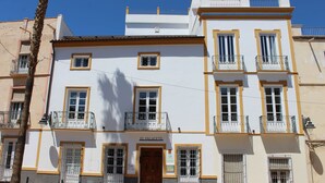 A multi-story building with balconies, a central entrance, and a sign reading "EL PALACETE".