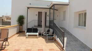 A rooftop terrace with a seating area, a potted plant, and a staircase leading to an upper level. - LARGE ROOM IDEAL FOR FAMILIES OR FRIENDS (Cuevas de Almanzora)