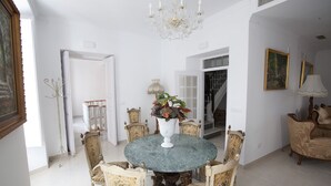 A dining area with a round table surrounded by ornate chairs, a chandelier, and a vase with flowers. - LARGE ROOM IDEAL FOR FAMILIES OR FRIENDS (Cuevas de Almanzora)