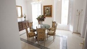 A dining area with a round table, six chairs, a chandelier, a large mirror, and a framed picture on the wall. - LARGE TWIN ROOM WITH PRIVATE TERRACE (Cuevas de Almanzora)