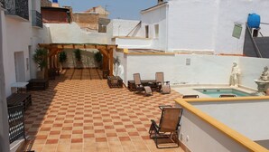 A courtyard with a tiled floor, outdoor seating, a small pool, and a statue. - LARGE TWIN ROOM WITH PRIVATE TERRACE (Cuevas de Almanzora)