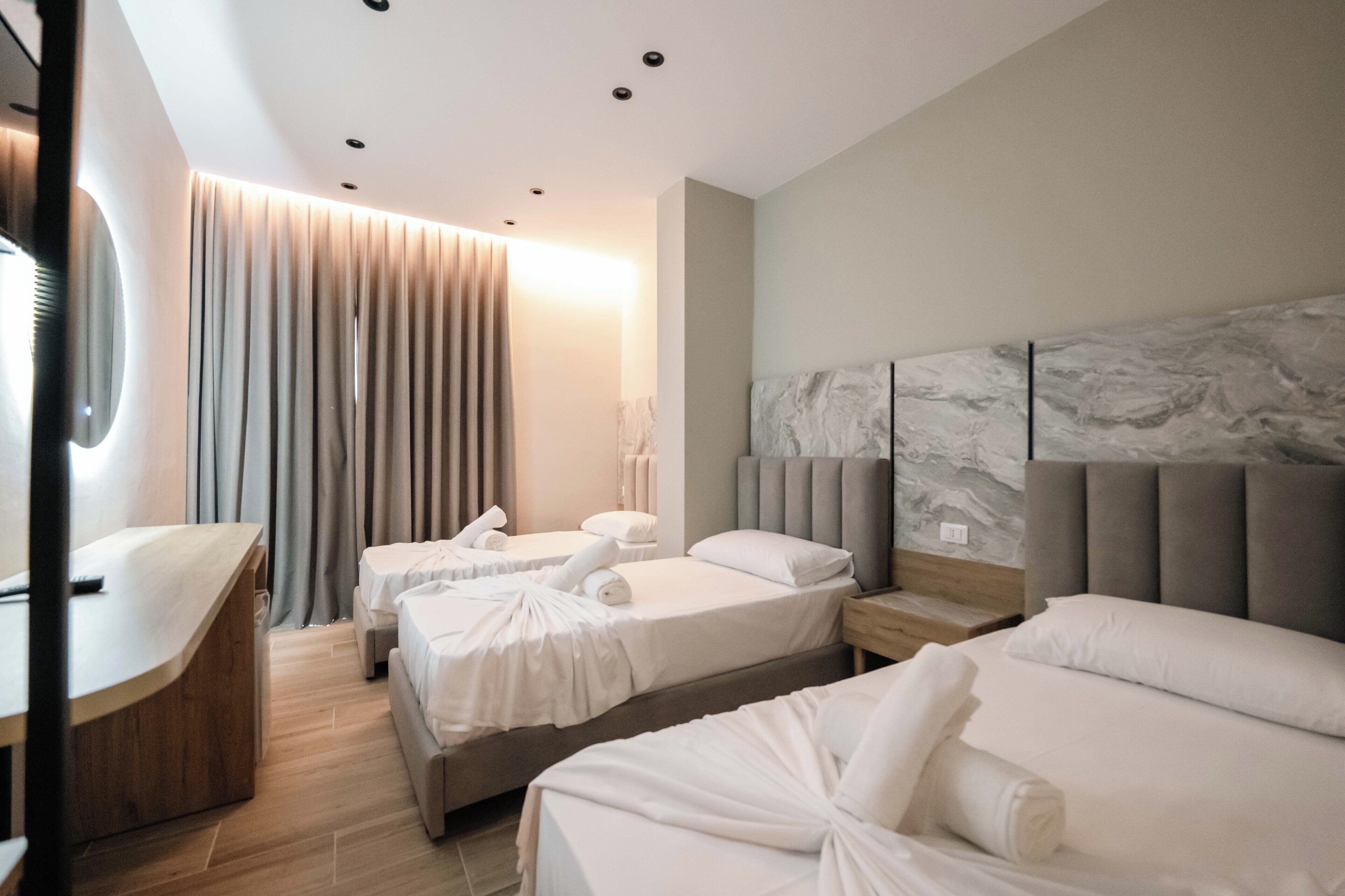 Habitació d'hotel moderna amb dos llits individuals, una taula de treball i un mirall gran.